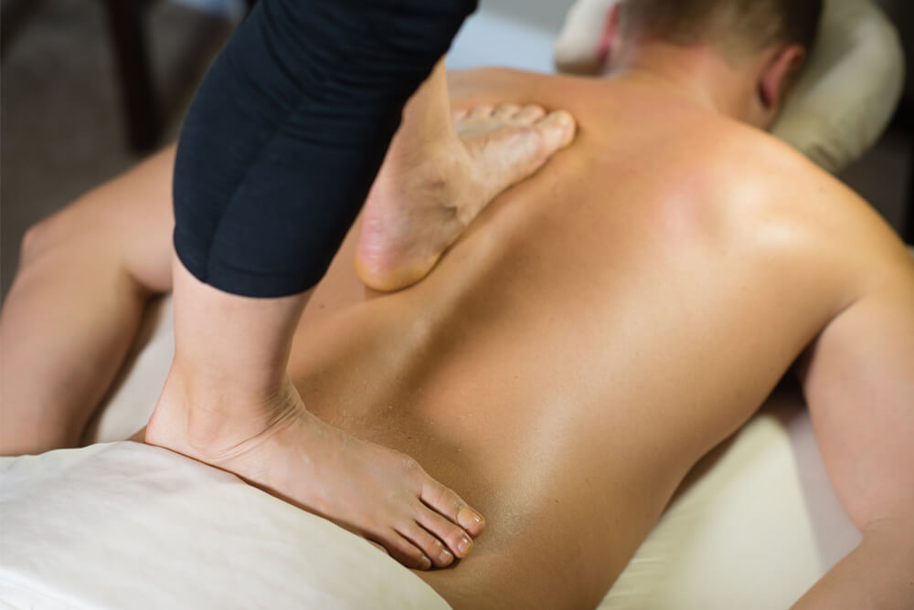 Woman giving back walking massage to client