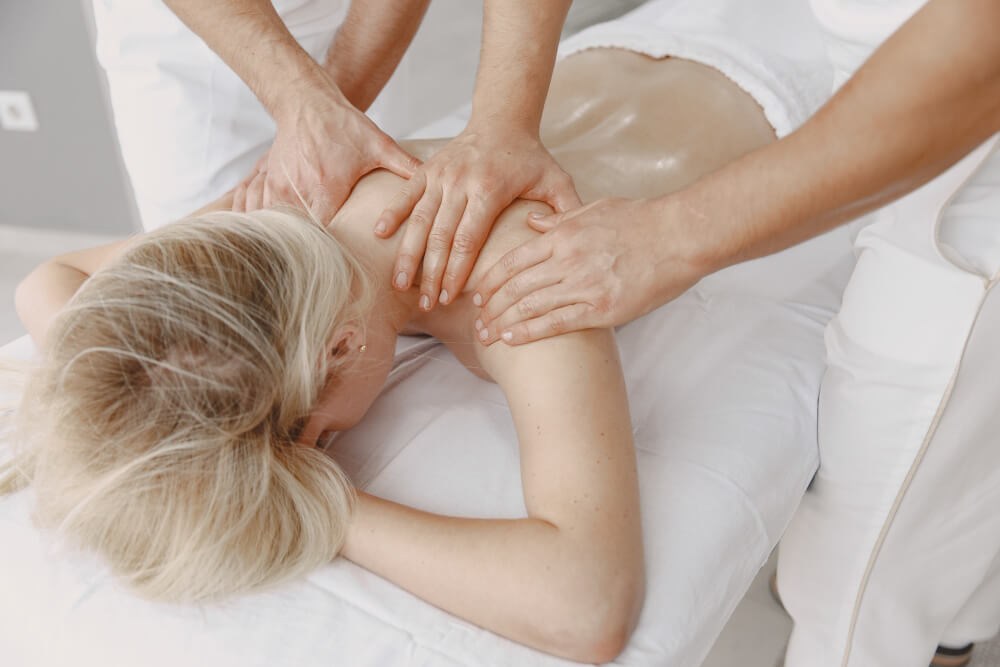Woman receiving a four hands massage by two massage therapists