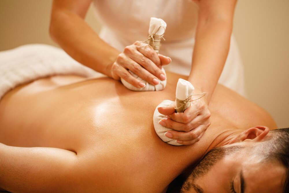 Man getting an herbal compress massage